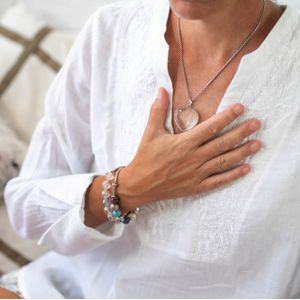 Woman sitting in a lotus position with right hand on heart chakra