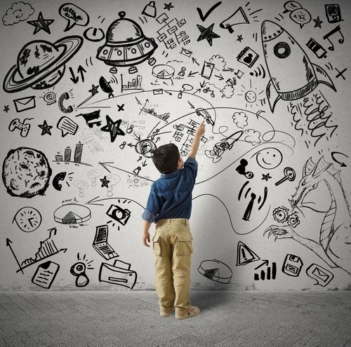 Little boy standing in front of a wall with drawings of all his passions