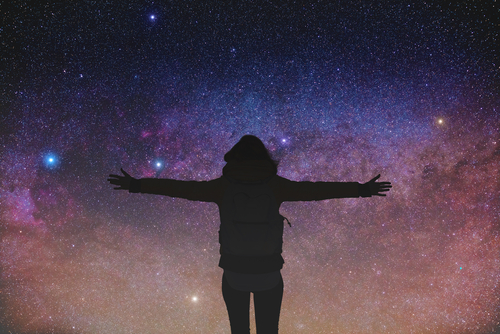 Silhouette of girl with arms open wide watching the stars.