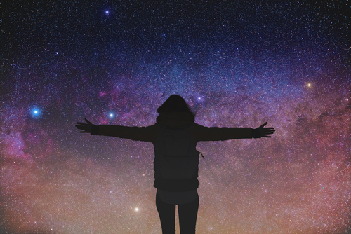Silhouette of girl with arms open wide watching the stars.