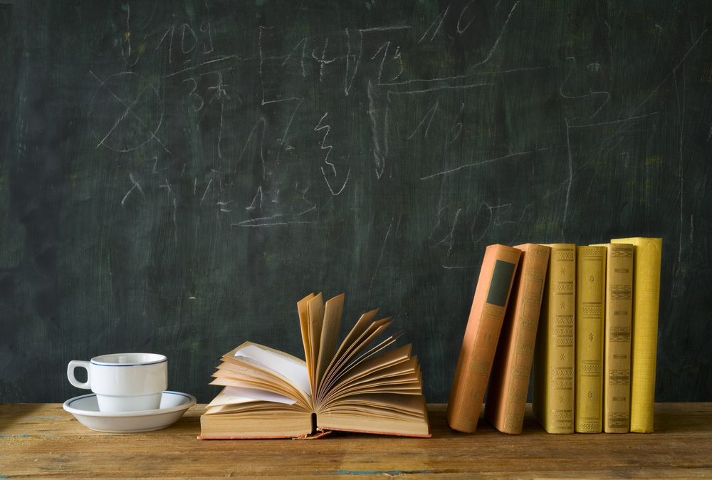 Books sitting on top of table with chalkboard in background