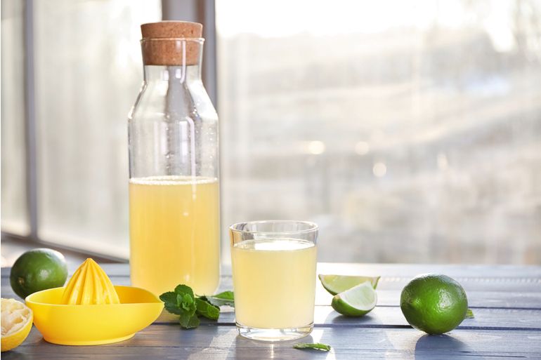 Fresh citrus drink in glassware and lime on table