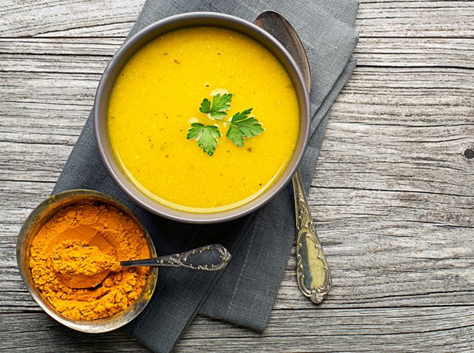 Healthy turmeric or curcuma cream soup on wooden background