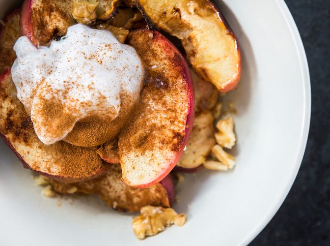 Red baked apples with cinnamon, walnuts and honey on a white background.