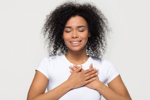 Smiling woman with hands over heart