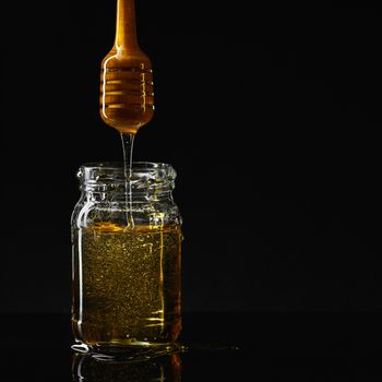 Jar with dipper and flowing liquid on the black background. 