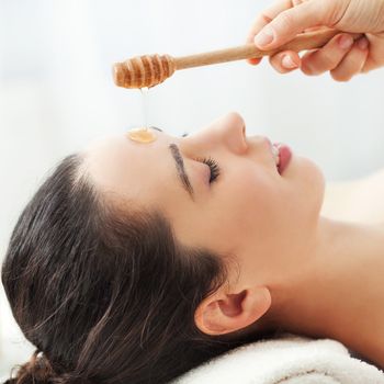 Woman having honey facial massage at spa salon