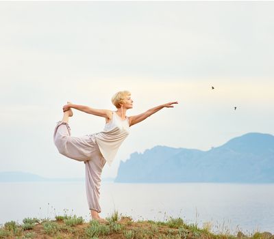 Senior woman doing yoga exercises with mountain on the background for balanced life