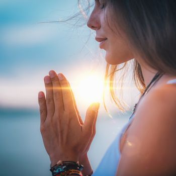 Young woman meditating with her eyes closed, practicing Yoga with hands in prayer position.