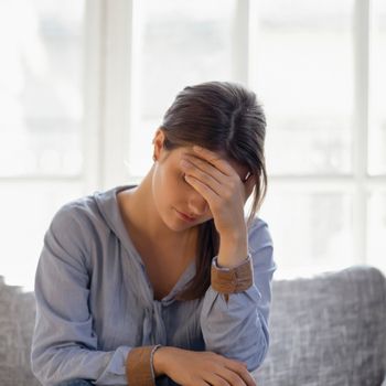 Woman with hand on forehead feeling drained